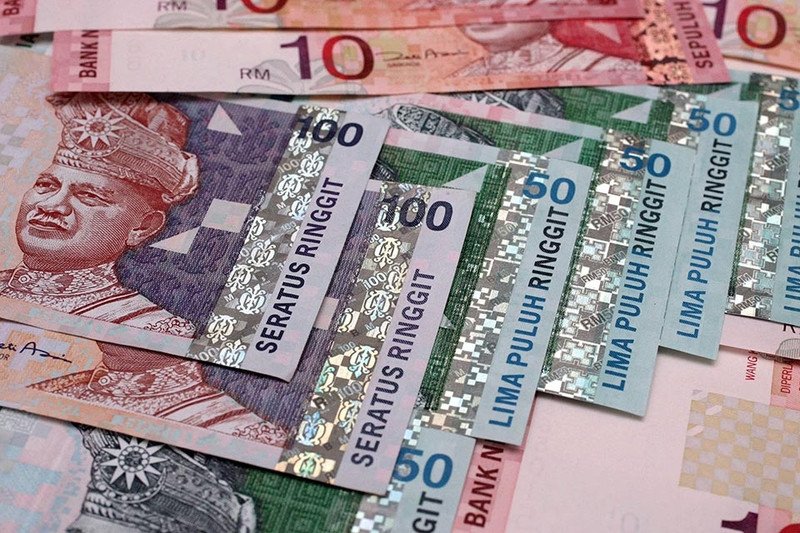 Hình ảnh một người đang cầm tiền Ringgit Malaysia và tiền Việt Nam, minh họa quá trình quy đổi tiền tệ.