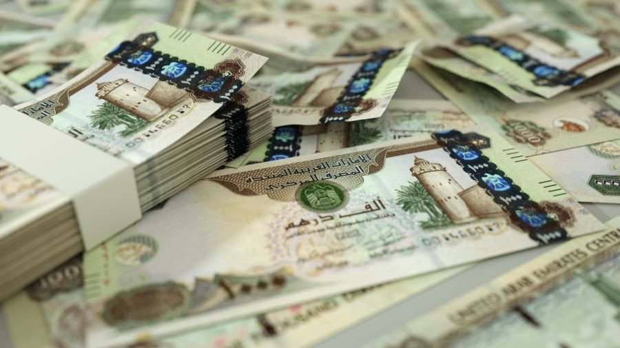 Một người đàn ông cầm những tờ tiền Dirham của Dubai, minh họa việc quy đổi tiền Dubai.