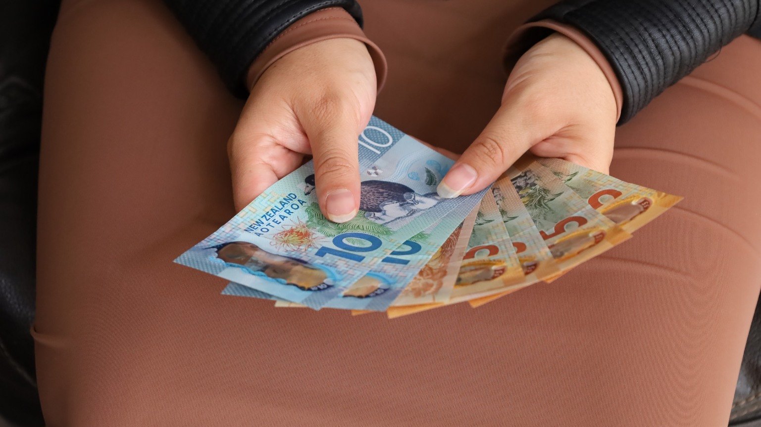 Người đang thực hiện giao dịch đổi tiền đô la New Zealand tại quầy giao dịch