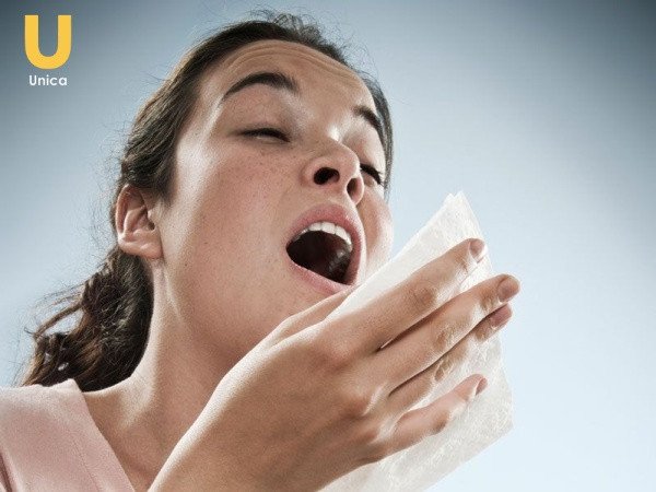 Người đàn ông đang hắt xì hơi, tay che miệng, thể hiện điềm báo nhảy mũi