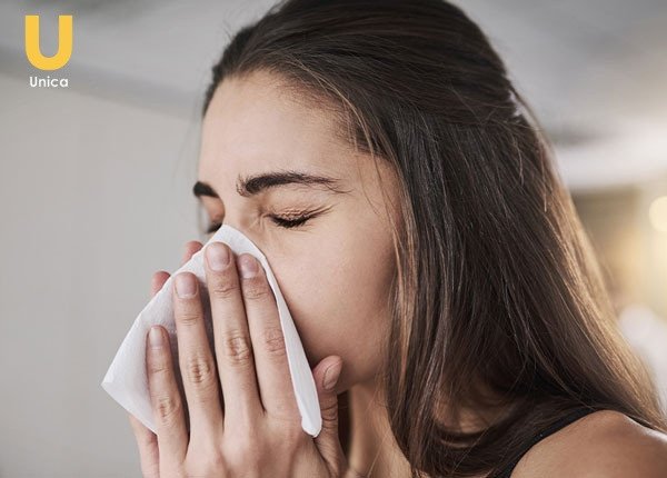 Người đang nhảy mũi ngồi bên bàn làm việc nhìn ra ngoài cửa sổ